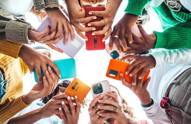 A circle of young people's hands, each holding a phone